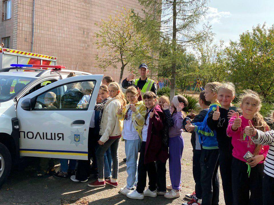 Учні оглядають службовий автомобіль поліції.