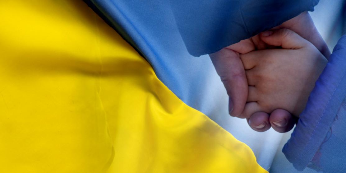 Мама тримає за руку дитину.