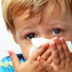 Дитина витирає носа носовичком.