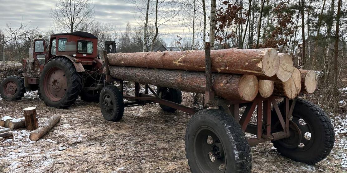 Трактор і причіп з деревиною.