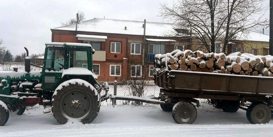 Трактор і причіп з деревиною.