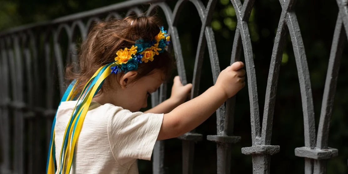 Маленька дівчинка тримається за огорожу.