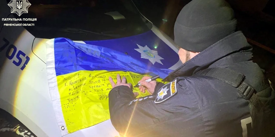 Патрульний підписує прапор.
