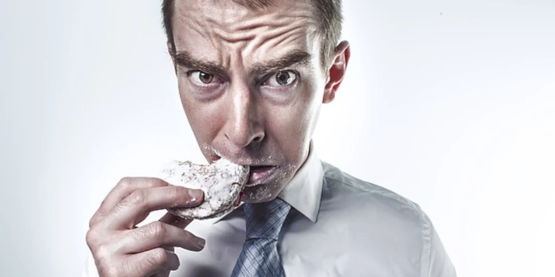 Основні помилки в харчуванні офісних працівників Чоловік їсть печиво.