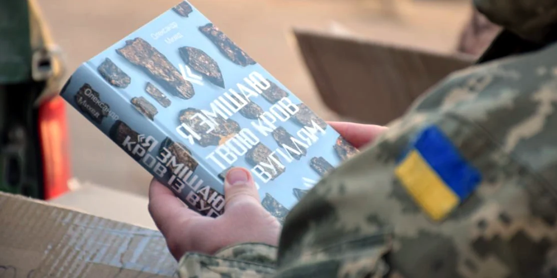 Військовий тримає книжку.