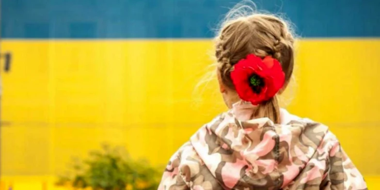 Дівчинка на фоні українського прапора.