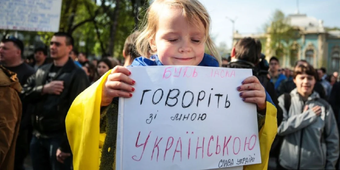 Дівчинка тримає плакат "Говоріть зі мною українською".