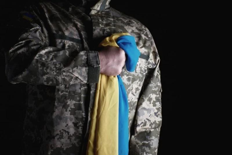 Вояк тримає прапор біля серця.