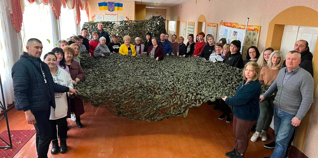 Учасники плетіння сіток позують зі сплетеною сіткою.
