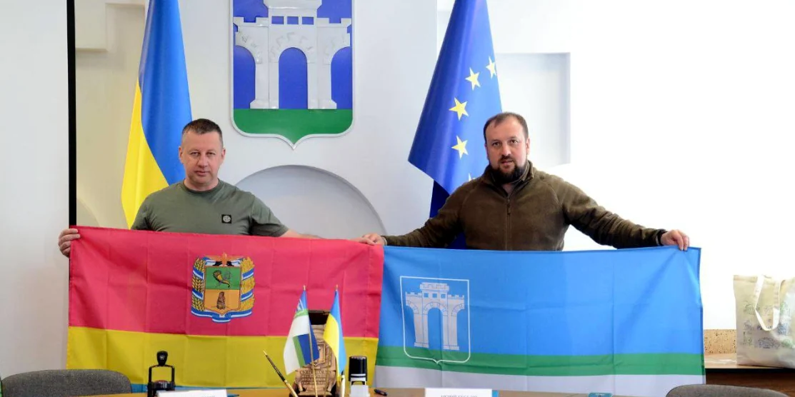 Віктор Шакирзян і Андрій Беседін тримають прапори міст.