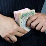 Чоловік ховає гроші у кишеню.