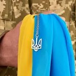 Військовий тримає прапор України.