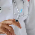 Лікарка тримає шприц.