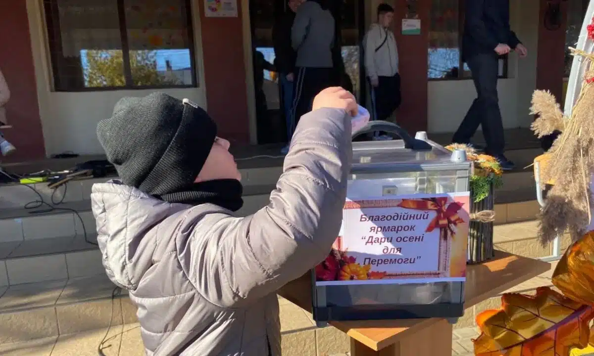 «Дари осені для Перемоги». Заклади освіти Радивилівської громади зібрали понад 115 тисяч гривень для ЗСУ (ФОТО) Учень кладе гроші до скриньки під час ярмарку «Дари осені для Перемоги».