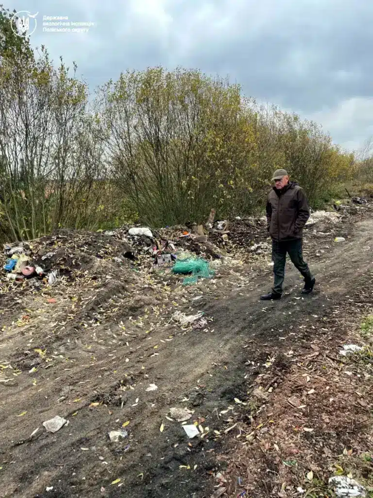 Інспектор ДЕІ Поліського округу оглядає стихійне сміттєзвалище.