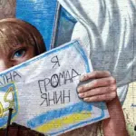 Мурал на стіні. Дівчина тримає від руки намальваний паспорт з написом "Я громадянин".