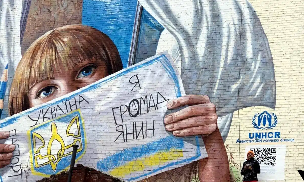 На Рівненщині запускають пілотний проєкт, що допоможе відновити громадянство людям із невизначеним статусом Мурал на стіні. Дівчина тримає від руки намальваний паспорт з написом "Я громадянин".