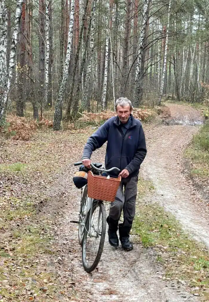 Грибник, що зник, іде з велосипедом лісовою дорогою.