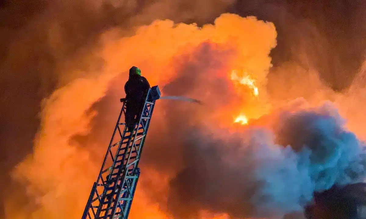 Пожежа на елеваторі. Пожежник на драбині поливає вогонь.
