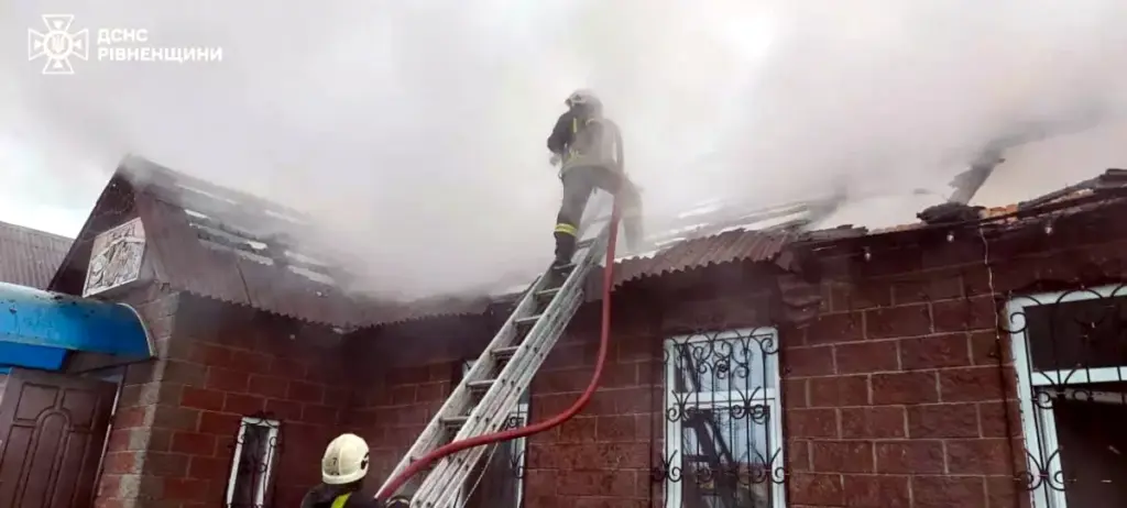Рятувальник на драбині гасить дах магазину.