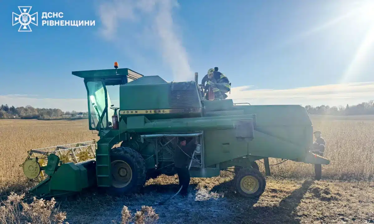 Рятувальник заливає з вогнегасника вогонь у моторному відсіці комбайна.