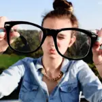 Як правильно чистити окуляри: прості поради для ідеальної чистоти та довговічності лінз Дівчина тримає брудні окуляри.