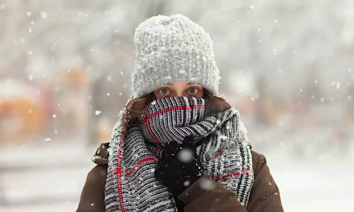 Дівчина закутана у шалик на засніженій вулиці.