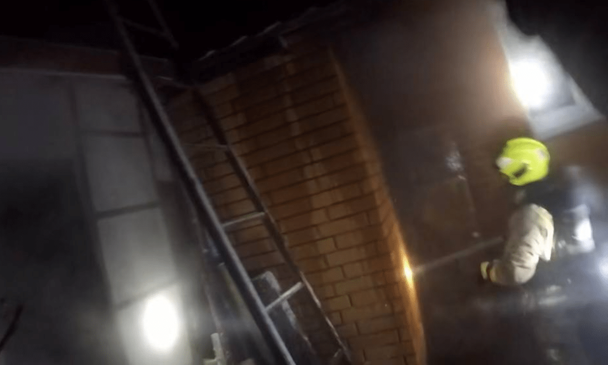 Рятувальник гасить пожежу на будинку.