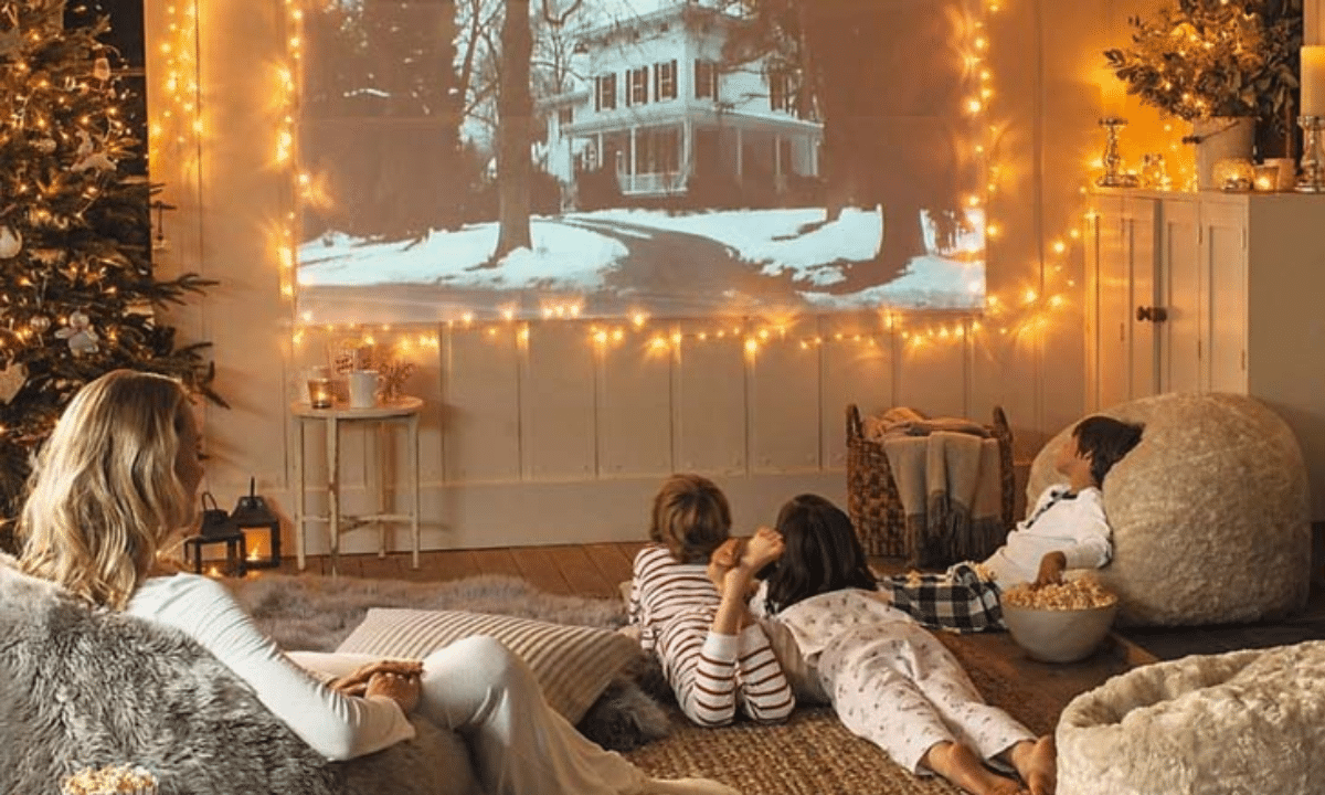 Сім’я з дітьми дивиться новорічний фільм удома: затишна кімната з ялинкою, гірляндами та святковою атмосферою.