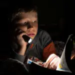 Графіки відключень електроенергії на Рівненщині у четвер, 11 грудня Хлопчик читає книжку з ліхтариком.