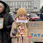 Мирна акція на підтримку військовополонених і зниклих безвісти відбулася у Корці Дівчинка тримає портрет батька і плакат під час акції у Корці.