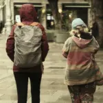 Двоє людей іде вулицею в дощ.