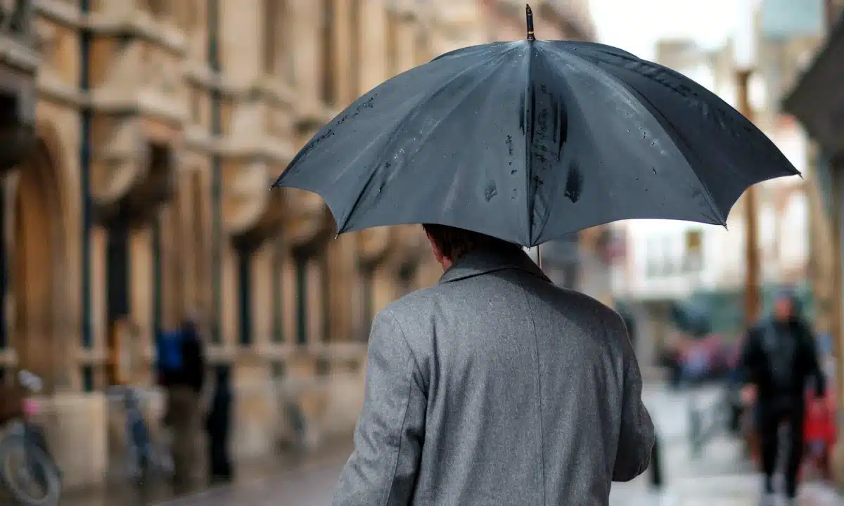 Чоловік з парасолею йде вулицею міста.