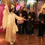 Діти спостерігають за виступом помічників Святого Миколая.