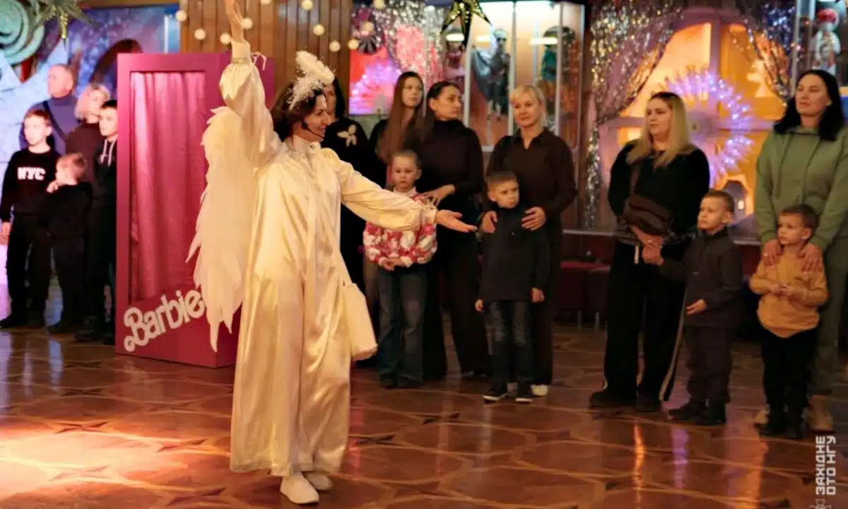 Діти спостерігають за виступом помічників Святого Миколая.