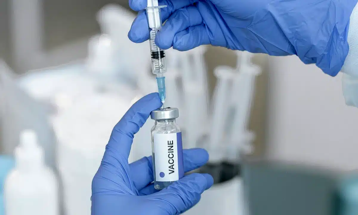 Медсестра набирає вакцину у шприц.