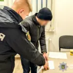 Чоловік, який зарізав товариша, підписує документи у поліцейському відділку.