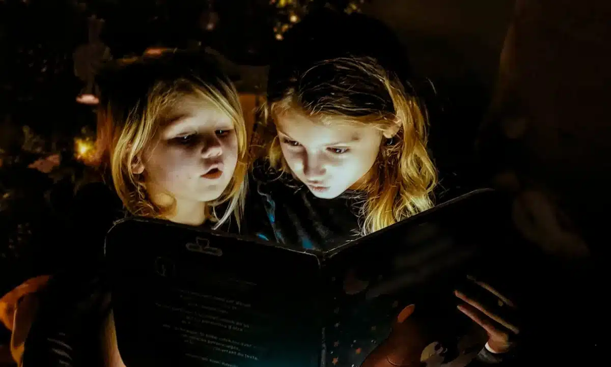 Дівчата читають книжку з ліхтариком.