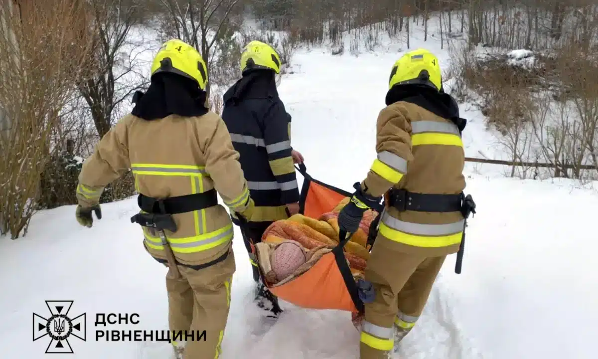 Рятувальники несуть хвору жінку.