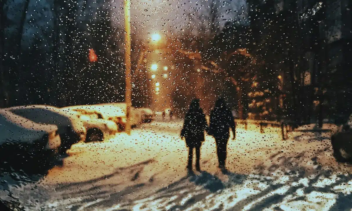 Якою буде погода на Рівненщині 27 січня. Часами дощ і мокрий сніг Двоє людей ідуть по снігу, падає дощ.