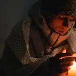 Хлопець гріє руки над свічкою.