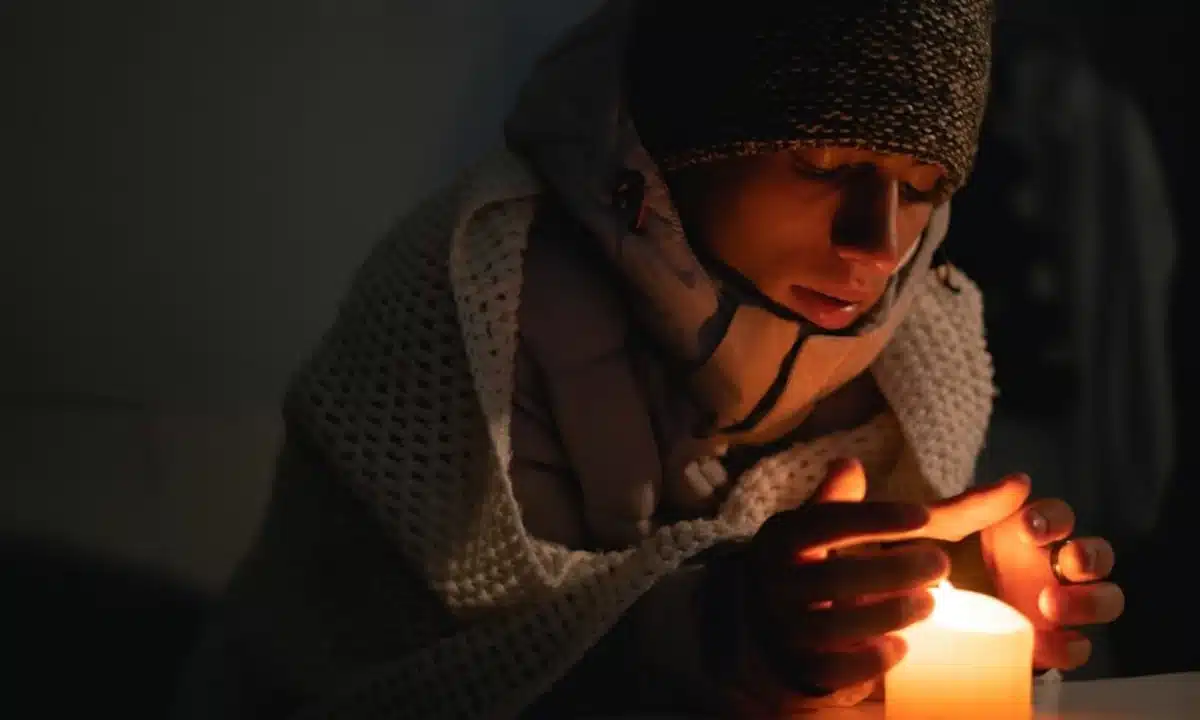 Хлопець гріє руки над свічкою.
