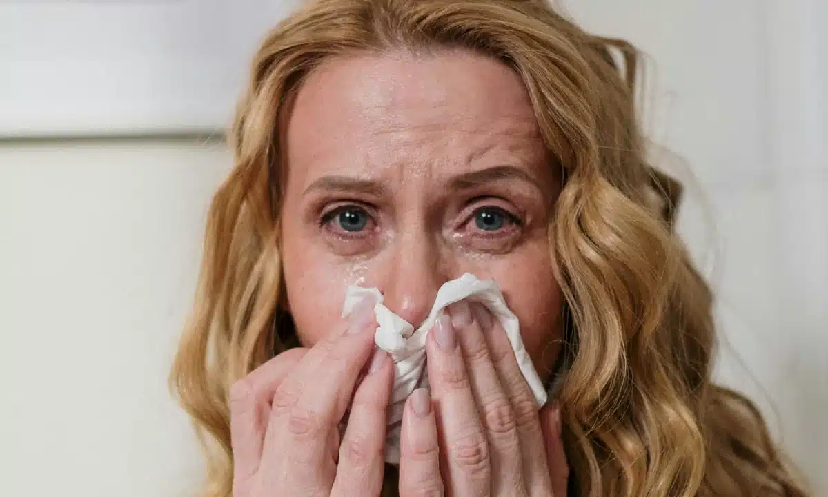 Жінка з ГРВІ витирає носовичком носа.