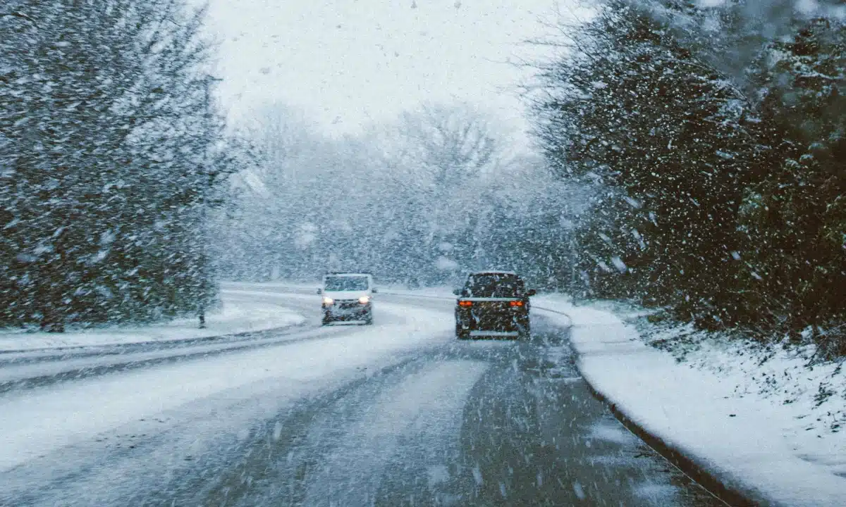 Два авто їдуть слизькою дорогою, падає сніг.