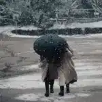 Дві жінки йдуть під парасолею.