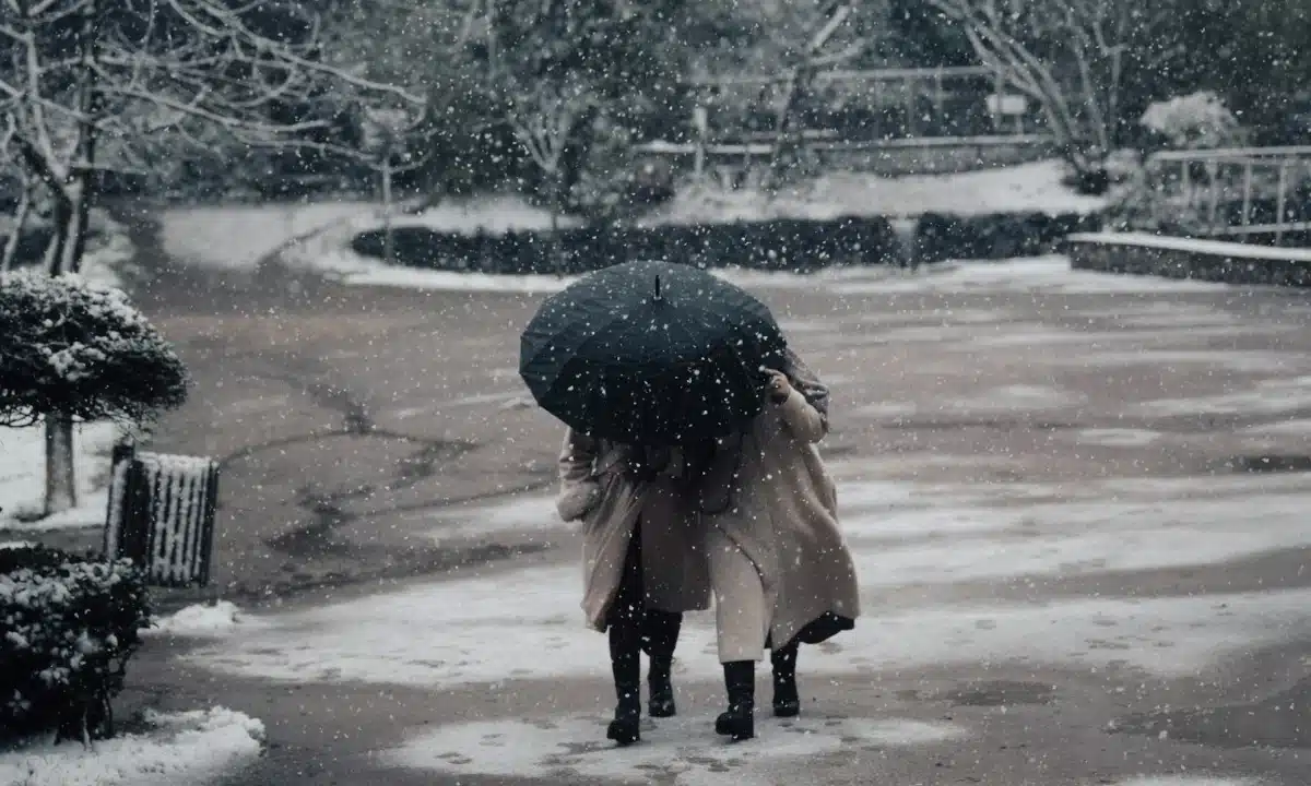 Дві жінки йдуть під парасолею.