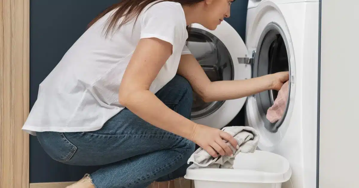 Жінка завантажує білизну в пральну машину ввечері вдома