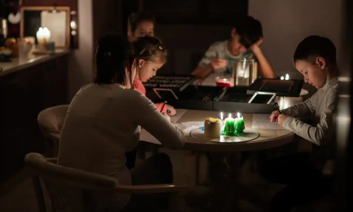 Графіки відключень електроенергії на Рівненщині у понеділок, 26 січня Родина сидить за столом при свічках.