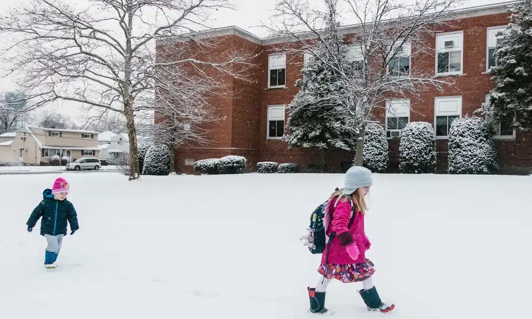Діти йдуть до школи по снігу.