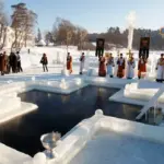 Ополонка у вигляді хреста. Довкола люди і священники.